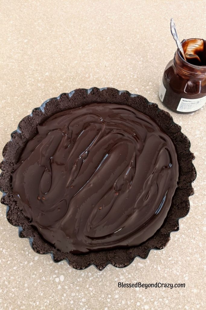 Overhead view of chocolate fudge spread over the bottom of chocolate cookie crumb crust