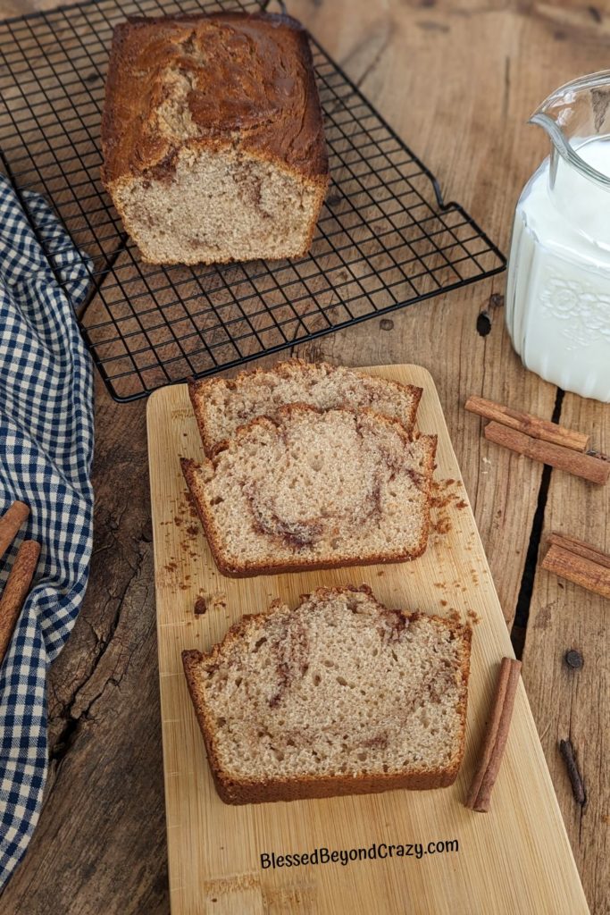 Loaf of cinnamon swirl coffee cake with three slices in foreground.